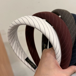 Detail view of colorful striped headbands with elegant white dotted lines and brand label