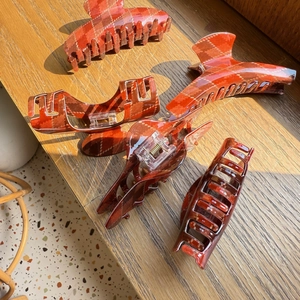 Detailed view of red plaid hair claws with metal spring on a warm wooden background