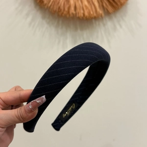 Detail of navy blue striped headband with fine knitted texture and gold inner logo