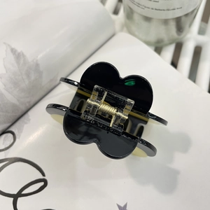 Elegant black flower hair claw clip with golden spring on a minimalist white background