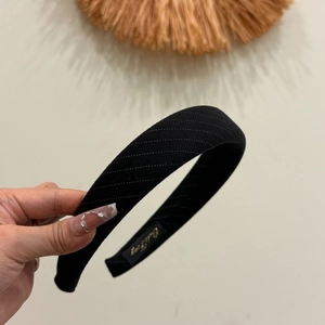 Close-up of black wide striped headband with textured fabric and Dalli Story brand label
