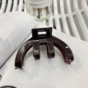 Elegant dark brown acetate hair claw clip with gold handmade lettering on white background
