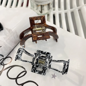 Close-up of elegant acetate hair claws in tortoise shell and marble patterns with gold springs