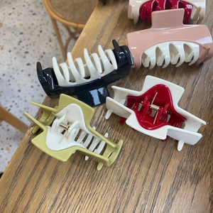 Detail view of large resin hair claws in black, pink, red and green color combinations