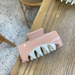 Pink and white bicolor hair claw clip with glossy finish on a wooden surface
