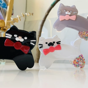 Detail view of cat-shaped acetate hair claws with bow ties and beaded tail accents