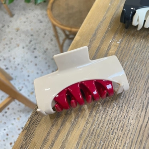 Macro detail of large hair claw clip in beige and red contrast glossy finish