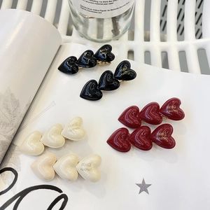 Détail de pinces à cheveux en forme de cœur en noir, bordeaux et couleur crème