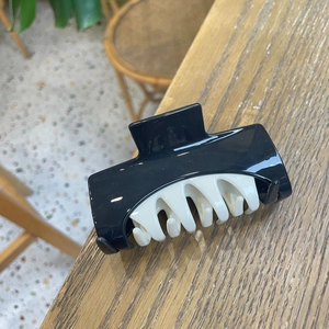 Detail view of a black and cream hair claw clip with contrast colors on wooden table