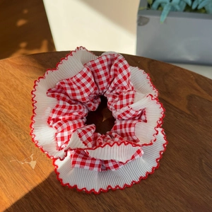 Plaid chiffon scrunchie with ruffled edges on a rustic wood table in afternoon sunlight