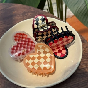 Detail of four acetate heart-shaped hair claws with plaid and floral patterns