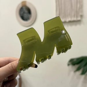 Dettaglio molletta per capelli a M in acetato verde oliva con strass e logo