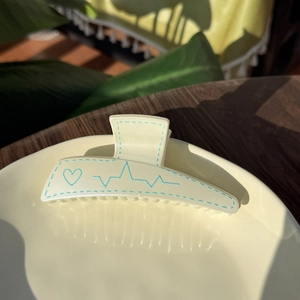 Pale yellow plastic hair claw clip with blue heart and heartbeat line pattern