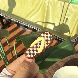 Detailed view of checkered acetate hair clip in creative flip-flop sandal shape