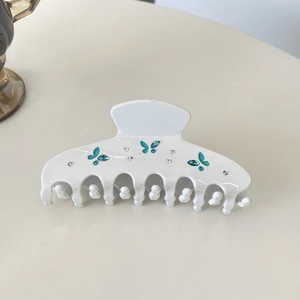 Détail d'une grande pince à cheveux blanche ornée de papillons en strass bleus