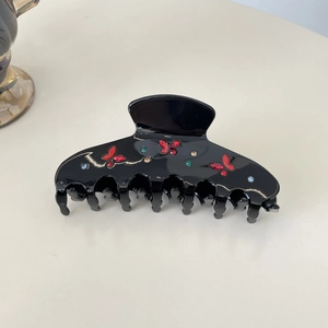 Détail d'une grande pince à cheveux noire brillante avec papillons rouges et strass colorés