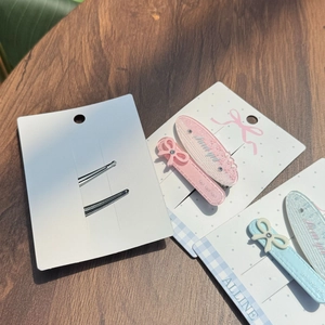 Détail de barrettes à paillettes roses et bleues avec nœuds sur carte de support