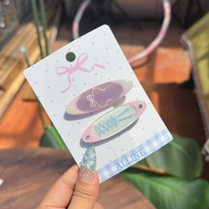 Close-up of pastel ballet-style bow and star hair clips on Alline display card