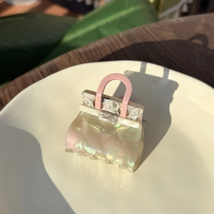 Close-up of a pearlescent acetate hair claw clip in a creative handbag shape design