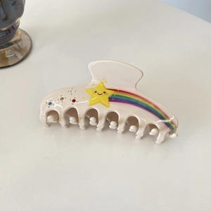Détail de la pince à cheveux crème avec motif étoile arc-en-ciel et strass colorés