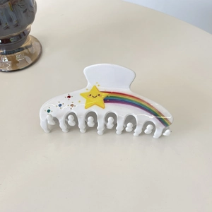Détail d'une pince à cheveux blanche avec motif étoile souriante jaune et arc-en-ciel