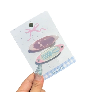 Pink and blue ballet-style bow hair clips with stars on display card for girls