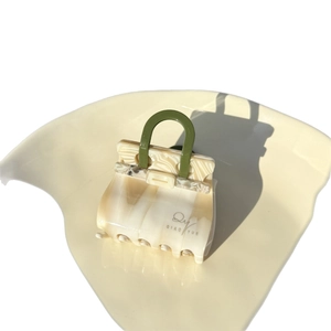 Miniature handbag-style acetate hair claw clip with cream marble pattern and green handle