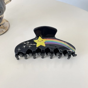 Détail d'une grande pince à cheveux noire avec une étoile souriante et arc-en-ciel