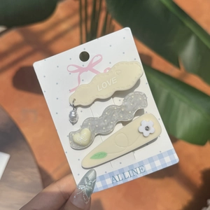 Set di tre fermagli per capelli con ciondoli a fiore e cuore su cartoncino