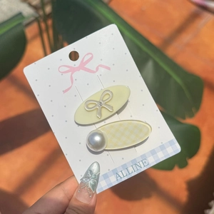 Lot de deux barrettes ovales avec nœud métallique et perle blanche sur carte de support