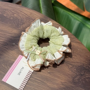 Sweet sea salt green scrunchie with polka dot bow and button on a rustic wood background