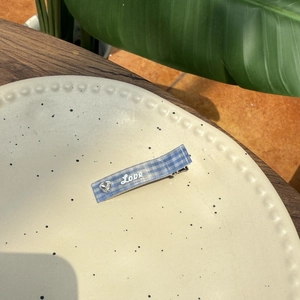 Détail d'une pince à cheveux à carreaux bleus avec texte LOVE et strass en forme de cœur
