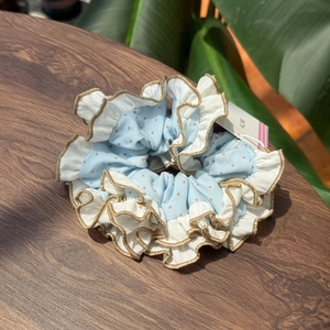 Detailed view of sea salt green scrunchie with gold polka dots and pleated ruffled edges