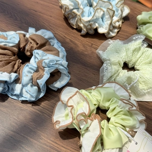 Detail shot of pleated scrunchies with wavy edges and various textures on a wood surface