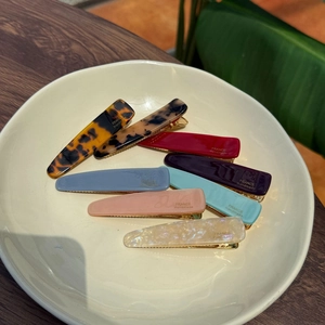 Dettaglio di un set di mollette in acetato colorato con scritta France Handmade oro