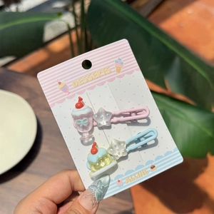 Detail of dessert-themed hair clips with ice cream and star charms on display card