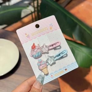 Close-up of resin hair clips set with pink ice cream and cupcake charms on card