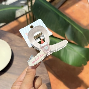 Detail showing hand-held pink sundae ice cream hair claw clip with sweet ice text design