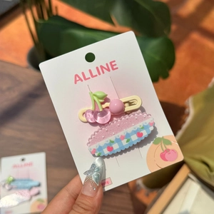 Détail de pinces à cheveux cerise avec paillettes roses et motif à carreaux sur carte