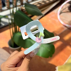 Détail d'une pince à cheveux à rayures bleues avec décor de cerises et mot cherry