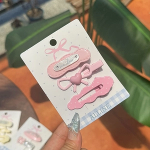 Three-piece pink hair clip set with heart, wave, and bow designs on a white card display