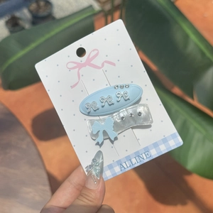 Close-up of blue bow hair clips with rhinestones on a display card in hand