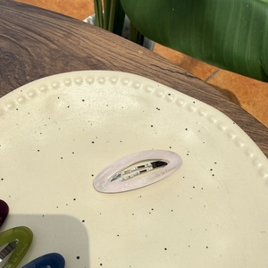 Elegant purple marble acetate hair clip with gold logo on a ceramic decorative plate