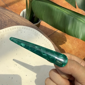 Detailed close-up of green marble acetate hair clip with golden handmade lettering