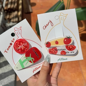 Detail showing red acrylic tomato hair clips set on display card in bright sunlight