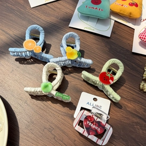 Detailed view of colorful fruit-themed hair clips and patterned scrunchie on wood