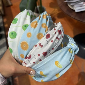 Close-up of four knotted fruit headbands featuring apple, orange, cherry, and lemon patterns