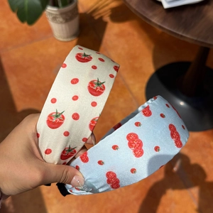 Detailed close-up of glossy satin headbands with fresh tomato prints in cream and light blue