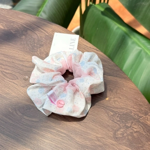 Détail d'un chouchou floral avec tulle rose et étiquette en tissu sur bois
