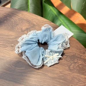 Détail d'un chouchou en dentelle bleu clair avec nœud blanc et perle sur bois